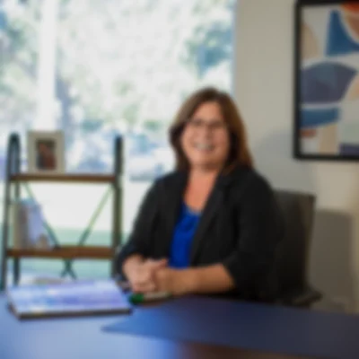 Woman seated at desk in blurred office staff photo